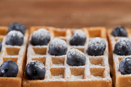 Waffles with blueberries powdered with sugar in a wooden boardの写真素材
