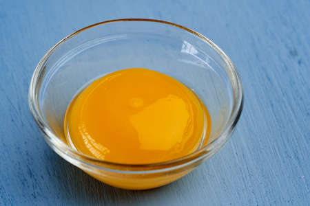 Raw egg yolk on blue backgroundの写真素材