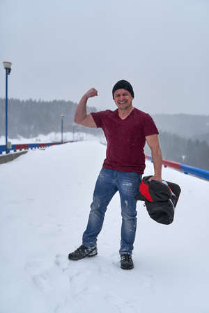 Strong man in t-shirt in the blizzard in the mountains during wintertimeの写真素材