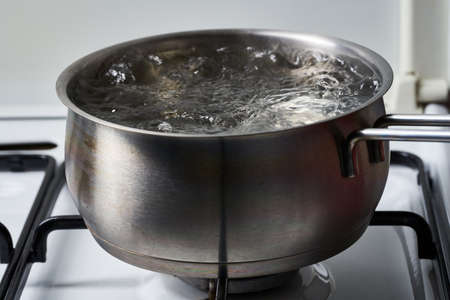 Stainless steel pot with water boiling on the gas stoveの写真素材
