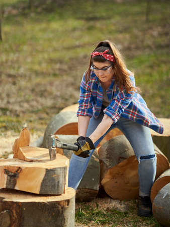 Strong woman lumberjack with her ax, splitting beech logsの写真素材