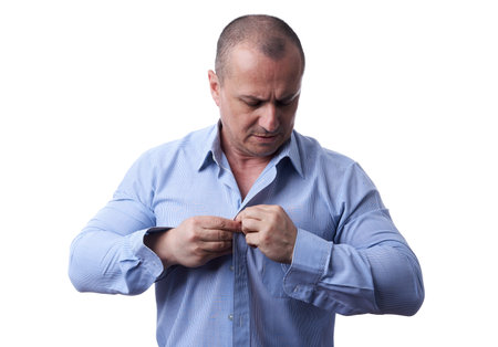 Businessman closing the buttons on his shirt, isolated on white background