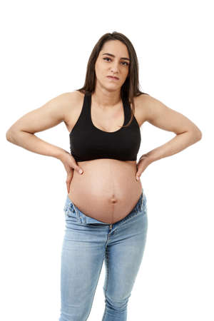 Pregnant woman displeased by her too tight jeans, isolated on white backgroundの写真素材