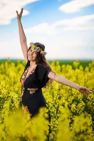Happy young pregnant woman in a canola fieldの写真素材