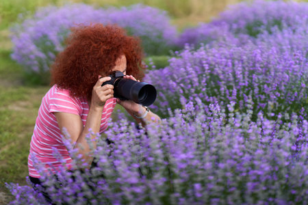 Woman nature photographer taking macro shots in a lavender field in bloomの写真素材