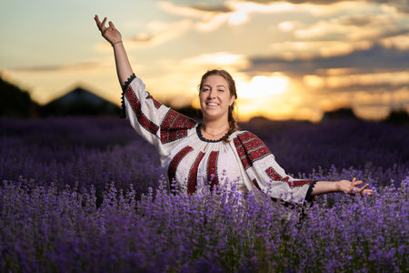Young woman in traditional Romanian costume harvesting lavender from her gardenの写真素材