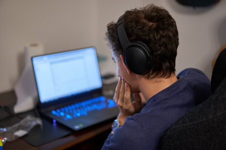 Young man working from home on his laptop on a busy deskの写真素材