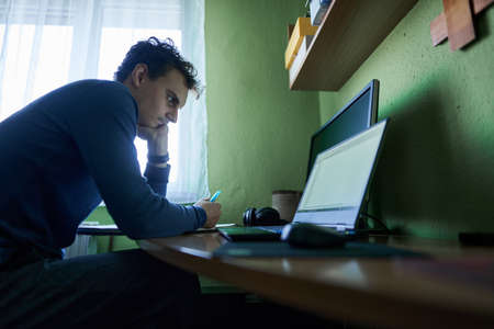 Software developer student working from home with laptop, computer, cellphone and notebook for his...