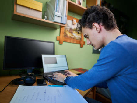 Software developer student working from home with laptop, computer, cellphone and notebook for his...