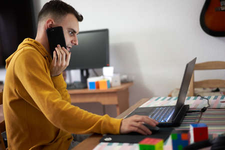 Student working from home with laptop, computer, cellphone and notebook for his pHd