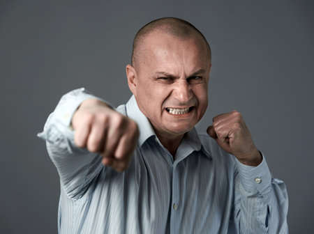 Angry businessman punching towards the camera in a rage, isolated on white backgroundの写真素材