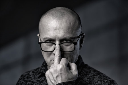 Businessman rising his glasses with an offensive gesture looking straight into the camera