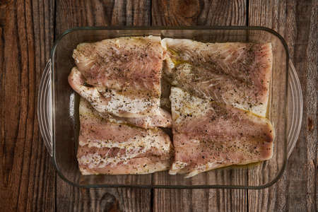 Seasoned zander fillets in a glass tray ready to go into the oven