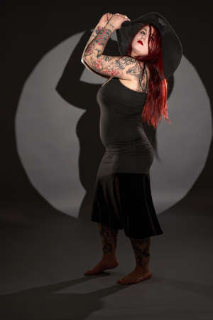 Size plus beautiful woman with tattoos, black dress and hat, glamour shotの写真素材