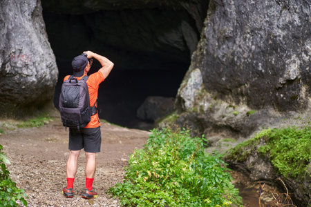 Hiker man with backpack exploring a cave in the limestone mountainsの写真素材