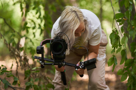 Nature videographer woman with camera on gimbal in the forestの写真素材