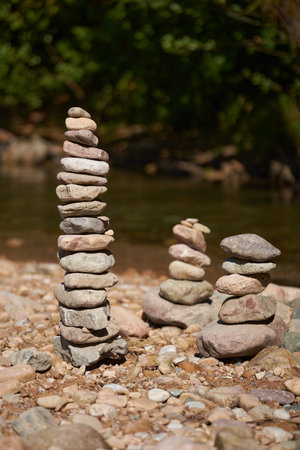 River pebbles and stones arranged in tower structures on the shoreの写真素材