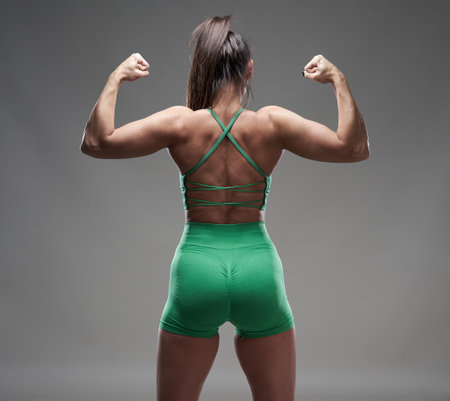 Attractive hispanic fitness model posing in gym attire on gray background, isolatedの写真素材