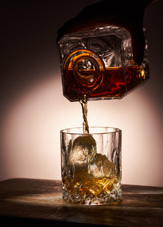 Pouring a glass of whisky from a decanter, lit from behind, stop motion shotの写真素材