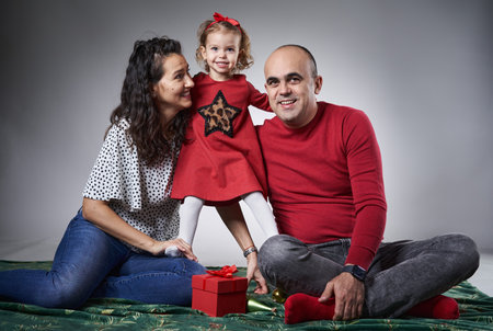 Happy young family with a young little girl and her parents, studio shot on gray background