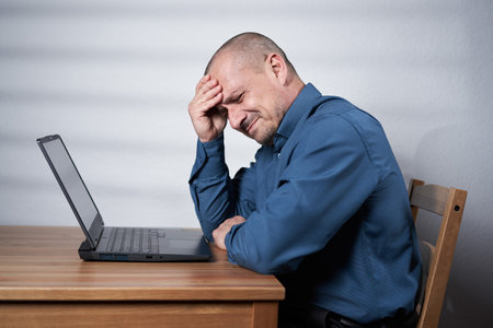 Businessman with a strong migraine holding his head, concept of overwork stressの写真素材