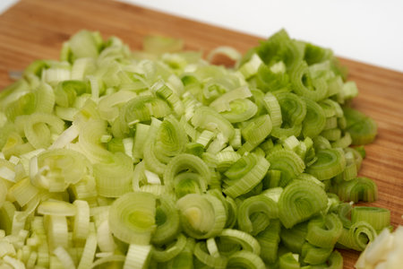 Closeup of fresh leek chopped on a wooden board for a recipeの写真素材