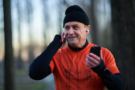 Runner answering a call on earphones during running, or putting music onの写真素材