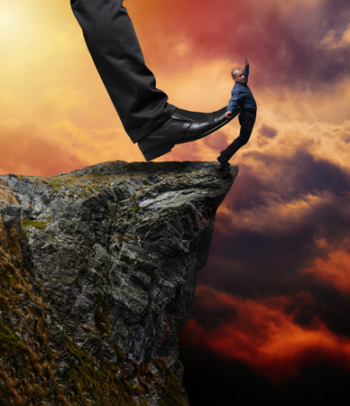 Businessman being kicked into abyss by a huge boss leg, concept of being fired from the workplaceの写真素材