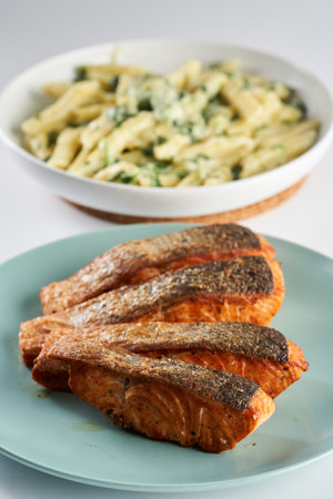 Salmon steak fried with garnish of penne rigate with blue cheese and broccoli asideの写真素材