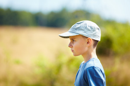 Candid profile portrait of a caucasian boy with cap outdoorの写真素材