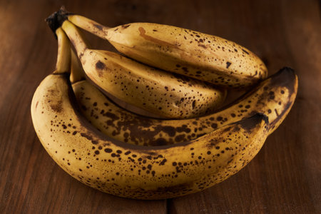 Overripe sweet banana bunch on a rustic wooden boardの写真素材