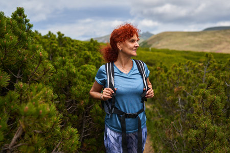 Woman hiker with backpack hiking on a trail in the alps at summertime