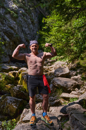 Shirtless athletic man posing standing in a river bed in the mountains after hikingの写真素材
