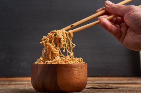 Wooden bowl with Chicken Pad Thai, a Korean noodles speciality, on a rustic wooden boardの写真素材