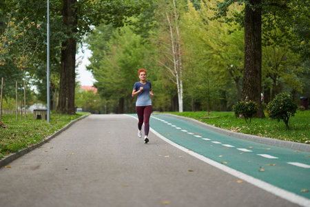 Athletic woman running in the park in the morning hours, early autumn, overcast