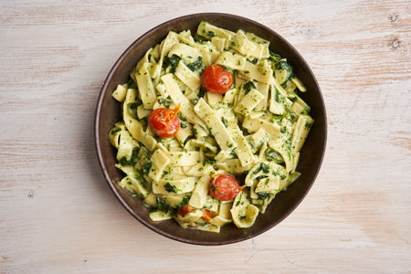 Penne rigate with blue cheese sauce and spinach and cherry tomatoes on a rustic wooden board