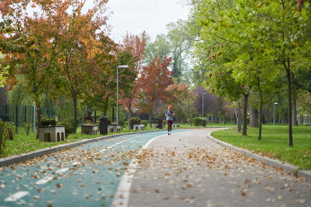 Athletic woman running in the park in the morning hours, early autumn, overcast