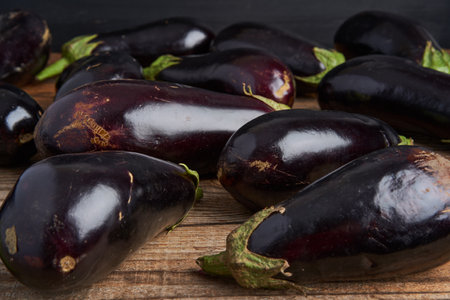 A pile of raw organic eggplants on a rustic wooden boardの写真素材