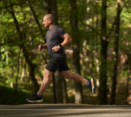 Athletic man running in park in the morning in the late summer early autumn
