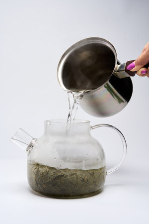 Making of Japanese Sencha tea isolated on white background, pouring hot water over dried leavesの写真素材
