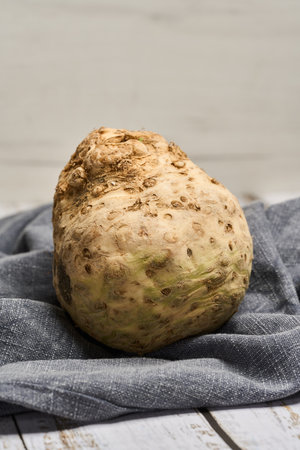 Closeup of a large celery root on a cloth on a wooden board