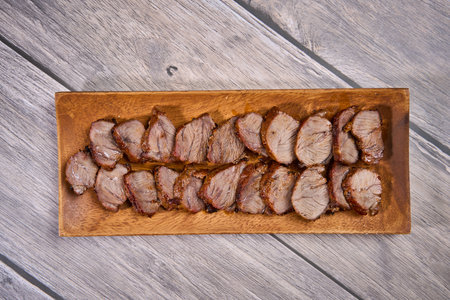 Grilled pork jowl fillets (cheeks) on a wooden boardの写真素材