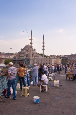 Men fishing on Galata Bridge which spans the Golden Horn in Istanbul, Turkey.There behind the Galata Towerのeditorial素材