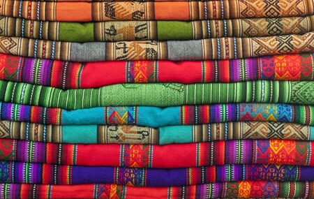 A pile of colorful Andean textiles photographed in the local handicraft market of Cusco, Peru