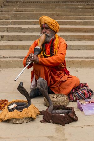 Varanasi, India - JANUARY 03, 2020: An Indian snake charmer is playing a traditional musical...