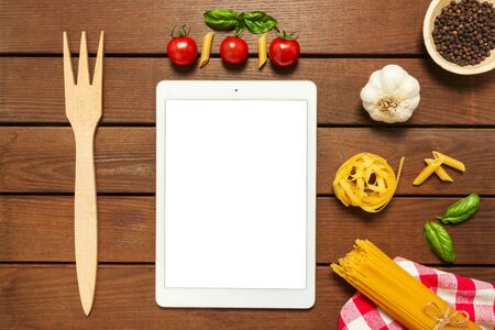 White tablet with copy space on a wooden background with ingredients for cooking Italian pasta, top viewの写真素材