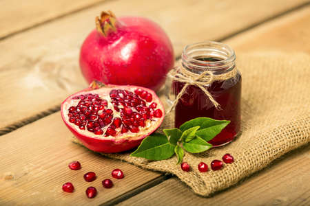 A glass of pomegranate juice with fresh pomegranate fruits on wooden table. Vitamins and minerals. Healthy drink concept.の写真素材