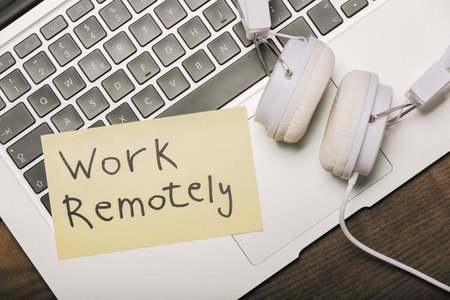 Work remotely. Memo stick on laptop keyboard with headset and pen. Modern technologies in business.