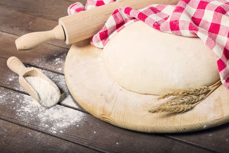 Fresh pasta on a table with ears of wheat, rolling pin, spoon with flour, and dish towel.の写真素材