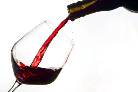 red wine poured from a bottle into wine glass on white background, isolatedの写真素材